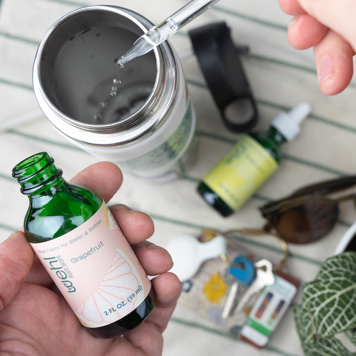 Grapefruit plant drops being added to water bottle with ginger lemon plant drops in background