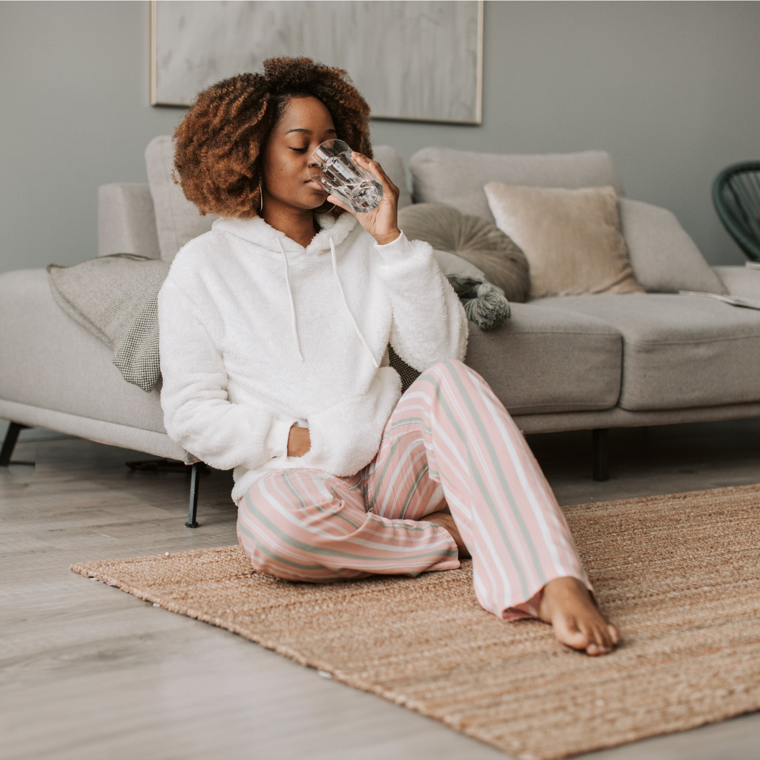woman drinking water with plant drops in living room